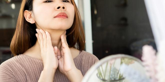 a woman rubbing her nodes on her neck below her jaw