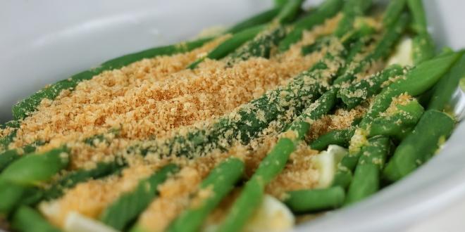 A plate of green beans topped with toasted bread crumbs