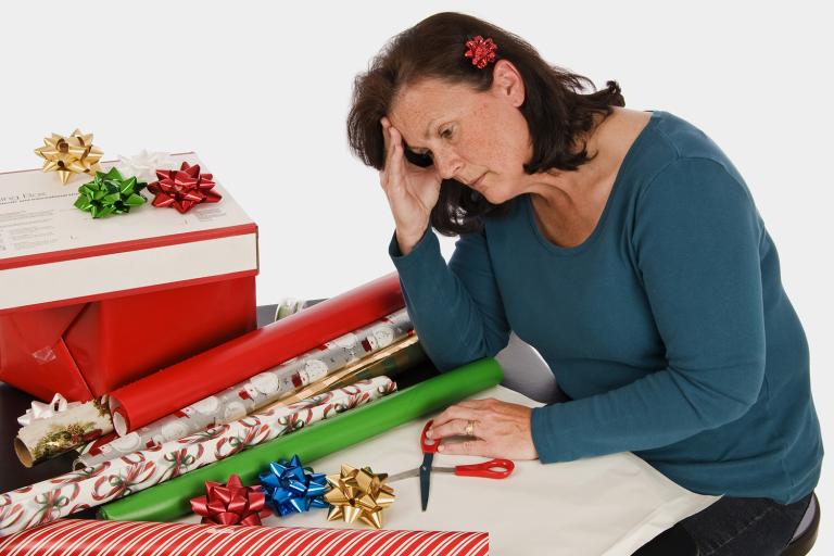 A very tired woman slouching in front of a pile of gift wrapping paper